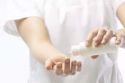 Woman in scrubs pouring lotion from a bottle into her other hand