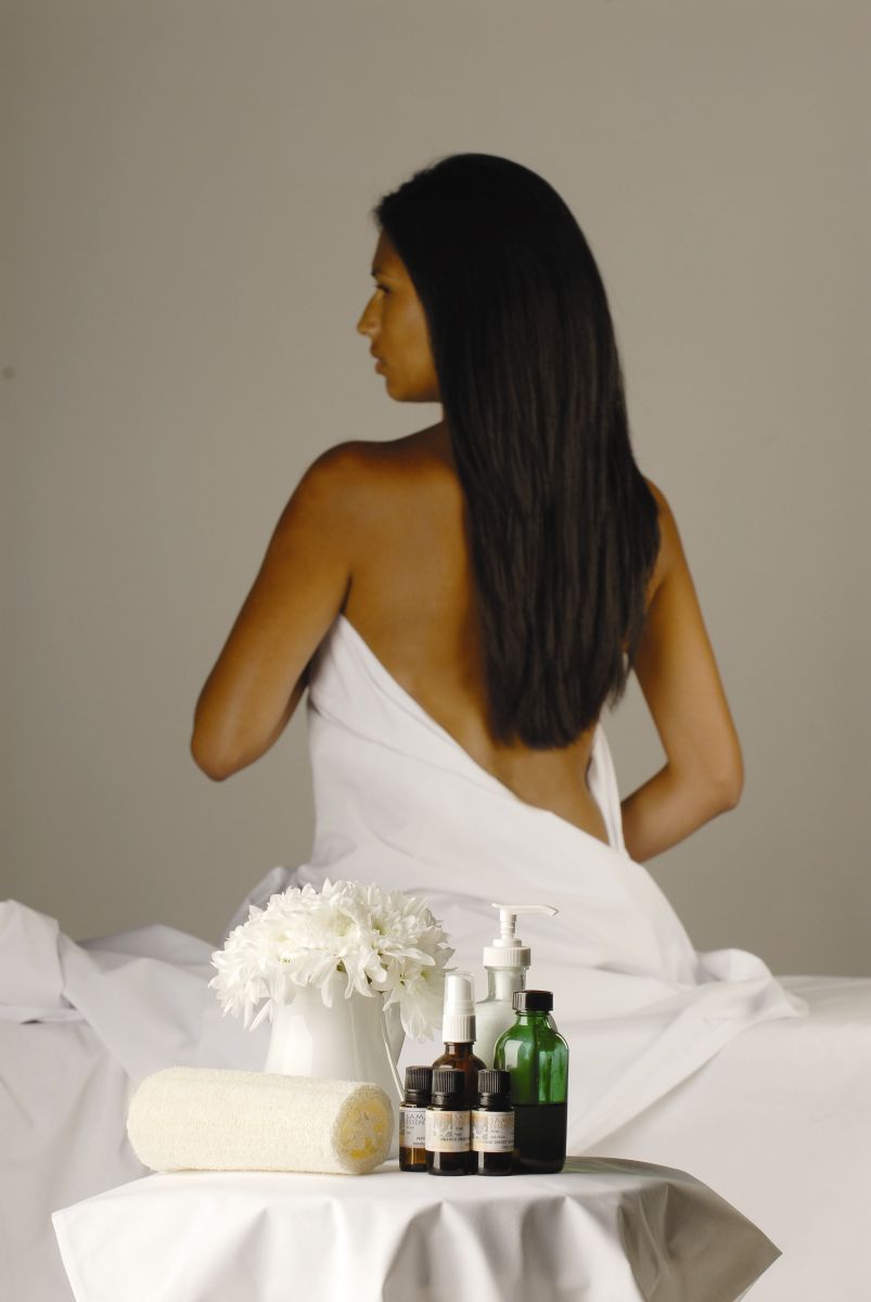 Young woman wrapped in towel sitting on massage table